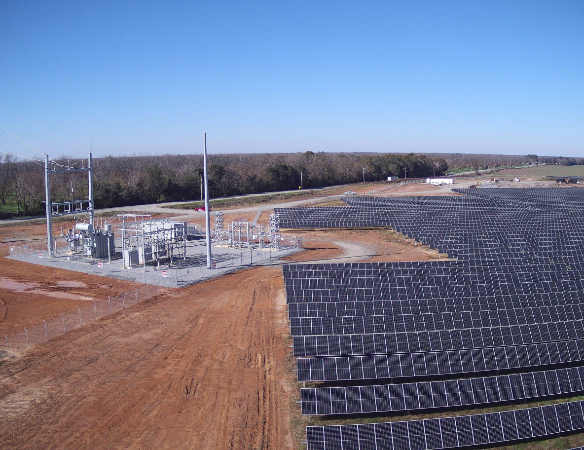 Aerial view of solar farm panels and small sub station.